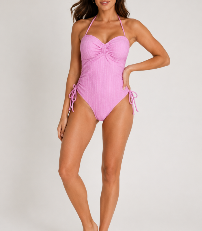 Modelo femenina luciendo vestido de baño enterizo rosa pastel texturizado para mujer con diseño halter y ajuste lateral, vista frontal y posterior, ideal para playa, piscina y verano.
